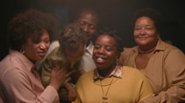 Siyah etnik kökenli neşeli çoklu kuşak ailesinin portre çekiminde Dolly, odada canlı ifadelerle, hafif ışıkla, yavaş çekimle aile fotoğrafı için poz veriyor.