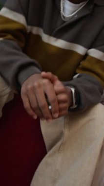 Kendine güvenen Afro-Amerikan genç bir çocuğun dikey yavaş portresi. Kameraya poz veriyor. Duvarın önünde bir sürü posterle rap hareketi yapıyor.