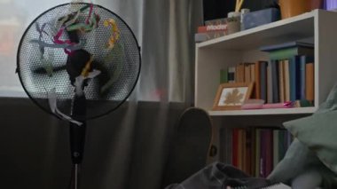 Yastıkların arasında yeşil ekran dizüstü bilgisayarın yanında uçan yelpaze, kitaplık ve defterlerle dolu rahat bir odada çekilen kimse yok.