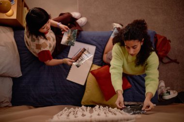 İki arkadaş rahat koltukta oturur, kitap okur, fikirleri paylaşır, sıcak ve samimi bir ortam yaratırlar.