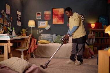 İyi dekore edilmiş, duvar resimleriyle dolu bir yatak odasını süpüren ve lamba ve kitap raflarıyla donatılmış rahat bir okuma köşesi olan biri.