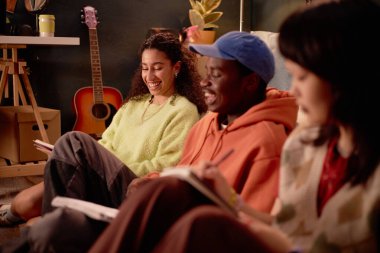 Arkadaşlar rahat bir ortamda oturur, günlüklerini yazar ve gülümserler. Arkaplanda bitkiler ve müzik aletleriyle sıcak, rahat bir atmosfer.