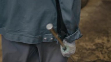 İş kıyafetleri içindeki tanınmayan tamircinin özel araba anahtarı tutarak arabaya yaklaşırken çekilmiş görüntüsü.