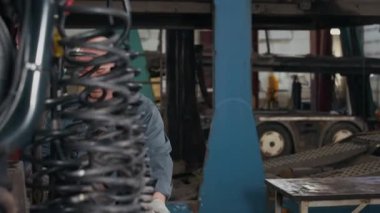 İş kıyafetleri ve pamuk eldivenli orta yaşlı beyaz erkek teknisyen teşhis için kırmızı kamyona tırmanıyor ve profesyonel oto tamirhanesinde çalışıyor.