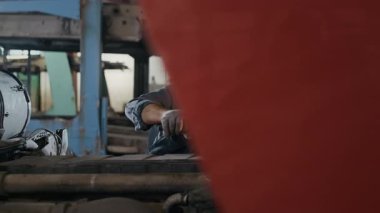 Profesyonel oto tamir atölyesinde çalışan, İngiliz anahtarı olan orta yaşlı, beyaz, erkek bir tamircinin orta boy fotoğrafı.