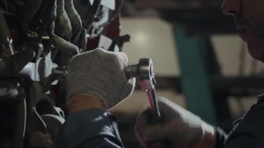 Araba servisindeki ingiliz anahtarı tamir aracını kullanarak, pamuk eldivenli tanınmayan bir tamircinin yakın plan çekimleri.