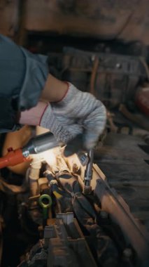 Garajda ingiliz anahtarı kullanan, pamuk eldivenli, tanınmayan işçilerin dikey kesilmiş resimleri.