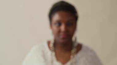 Genç Afrikalı Amerikalı kadının yakın plan portre fotoğrafını yakınlaştır. Uzun küpeler ve saç bandı doğrudan kameraya bakıyor.