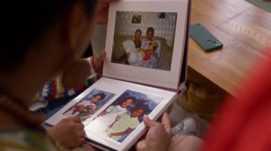 Tanımlanamayan kadınların elinde resimli açık fotoğraf albümüyle omuz üstü çekimleri ve birlikte bakmaları.