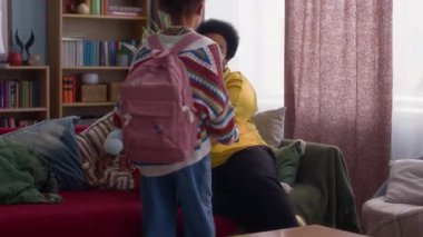 Sevgi dolu Afrikalı Amerikalı büyükanne renkli oturma odasında torunlarından ikisini görüyor.