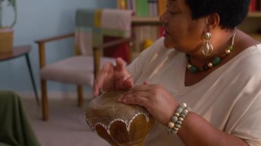 Torunu ukulele çalarken, Afro-Amerikan kadın, rahat ve renkli oturma odasında otururken,