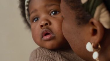 Afrika kökenli Amerikalı bir annenin bebeğini yanağından öptüğü yakın plan bir fotoğraf.