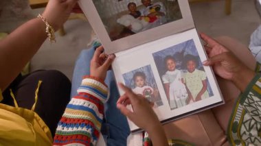 Tanımlanamayan üç kişinin yan yana oturup eski günleri anarak fotoğraf albümlerine baktığı en iyi görüntü.