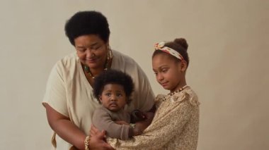 Gülümseyen ve ilgili Afrikalı Afrikalı Amerikalı büyükannenin iki torunuyla kameraya poz verdiği portresi.