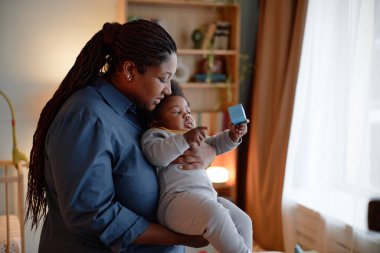 Siyahi anneyi orta derecede severken, bebeğin bebeğini nazikçe yatak odasında yatırırken, bebeğin yapı bloğunun küp parçasıyla oynarken, huzurlu uyku saati rutini, fotokopi odası.