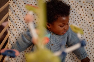 Mavi örgü bir şamata giymiş, çocuk odasında beşiğinde yatan tatlı, uyuyan siyah kızın en güzel manzarası.