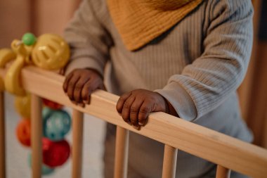 Siyah kızın küçük ellerine yaklaş, rahat mavi tulumlar giyin, beşiğinde tahta levhalar tut, sıcak ışıklarla, fotokopi çektir.