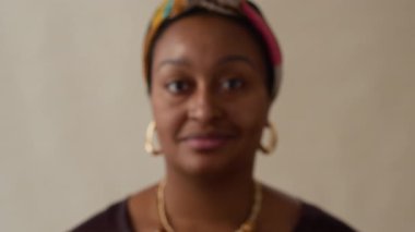 Renkli başörtüsü ve büyük halka küpeler takan gülümseyen Afrikalı Amerikalı kadının portre fotoğrafını yakınlaştırın.