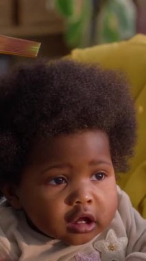 Küçük torununun kıvırcık saçlarını tarayan Afrikalı Amerikalı kadının, rahat oturma odasında dikey yatay pozu.