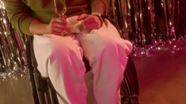 Kameraya bakıp, şampanya kadehini kaldıran, arka planda parlak folyo perdeleri ve balonlarla engelli, neşeli beyaz adamın portresini kaldır.