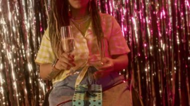 Dans ederken kameraya poz veren, elinde şampanya kadehi tutan ve doğum günü partisinin keyfini çıkaran rahat, beyaz kadın portresini kaldır.