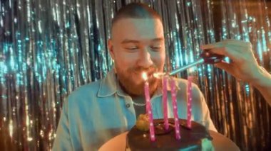 Doğum günü pastasına bakıp mum üflemeyi beklerken partideki tanınmayan bir arkadaşın mumlarını yakmasını bekleyen heyecanlı beyaz adamın yavaş çekimleri.