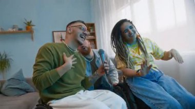 Orta ölçekli, tekerlekli sandalyede eğlenen, mikrofona karaoke şarkıları söyleyen, dans eden ve rahat oturma odasında kahkahalarla gülen beyaz arkadaşlarla dolu.