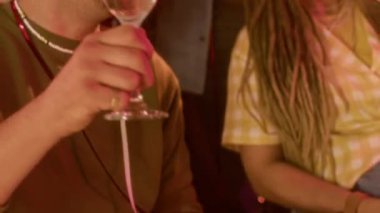 Bardaklarını tokuşturup şampanya içen, parlak alüminyum folyo perdelere karşı duran ve birlikte eğlenen bir grup mutlu genç arkadaş.