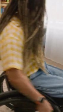 Tekerlekli sandalyede daireler çizip birbirlerine yetişmeye çalışan, gülen ve evde eğlenen, engelli, neşeli, genç beyaz arkadaşların el kamerası görüntüleri.