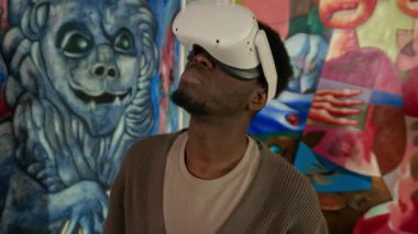 Sanal gerçeklikteki soyut sanat sergisini keşfederken VR kulaklıklı genç Afrikalı Amerikalı erkek galeri ziyaretçisinin yakın çekimleri.