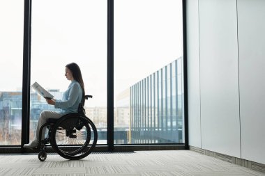 Tekerlekli sandalyedeki genç iş kadınının çizimsel yan görüntüsü ofis penceresinden dokümanları okuyor, boşluğu kopyalıyor.