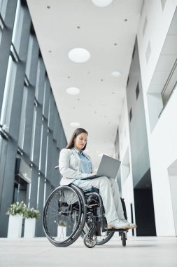 Tekerlekli sandalyedeki başarılı iş kadınının dikey düşük açılı portresi ofis lobisinde laptop kullanarak, boşluğu kopyala