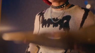Koyu renk süveter giyen punk bir kızın davul çalarken, ses geçirmez stüdyoda davul çalarken.
