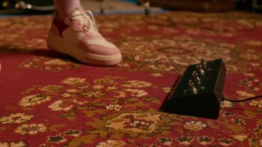 Performans sırasında müzik stüdyosunda siyah gitar efektleri pedalına basan, beyaz ve pembe ayakkabılı, tanınmayan bir ayağı yakından çek.