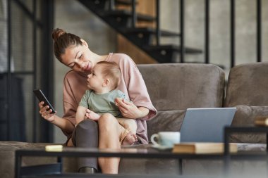 Özürlü modern bir annenin portresi. Evinde çalışıyor ve sevimli bir çocuğu kucağında tutuyor.