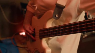 Gen Z kızının müzik stüdyosundaki prova sırasında basgitarını titizlikle akort ettiği yakın çekim.