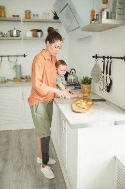 Mutfakta yemek pişirirken engelli bir annenin dikey portresi.