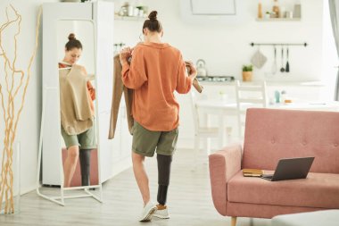 Özürlü modern bir kadının arka plan portresi aynaya bakarken rahat bir ev içinde kıyafet denerken, boşluğu kopyala
