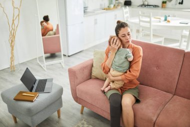 Engelli modern anne portresi bebek kucağında rahat bir evde kanepede otururken, boşluğu kopyalayarak