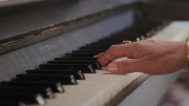 Klasik yüzük ve bileklikle donatılmış, kapalı mekanda piyano tuşlarıyla çalan tanınmamış, zarif müzisyenin eli.