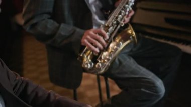 Orta yaşlı, çift ırklı bir kadının canlı giyinmiş, saksafoncu ve perküsyonist düetin duygusal caz performansını dinlerken, rahat, sıcak, aydınlık bir barda canlı müzik çalarken.