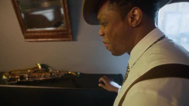 Eski moda giyinmiş Afrikalı Amerikalı caz müzisyenleri sahne arkasında samimi bir gülümseme gösteriden önce ya da sonra ritim ve enerji yayıyor.