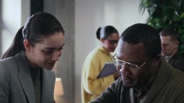 Modern yeşil ofiste birlikte çalışarak iş projesi için fikir alışverişinde bulunan bir grup genç iş arkadaşının dikkati dağıldı.