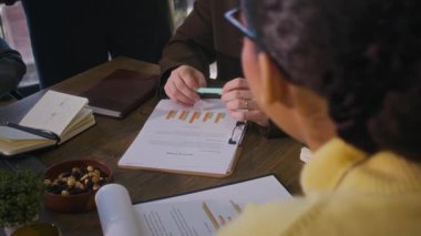 Formalite icabı beyaz bir erkek çalışanın masada oturup iş projesini tartışmasını ve modern yeşil ofiste birlikte çalışmasını yavaş çekim yapın.