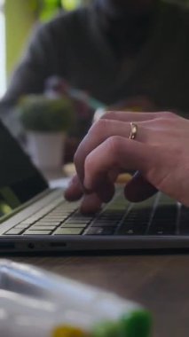 Masada oturan ve laptopta bulanık arka planda oturan kişi tarafından tanınmayan birinin dikey kesilmiş resimleri.