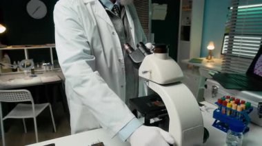 Laboratuvarda modern teknolojiyi kullanarak mikroskoptan elde edilen dijital büyütülmüş görüntülerle laboratuvar önlüklü, konsantre olmuş, beyaz erkek mikrobiyolog görüntülerini yukarı kaldır.