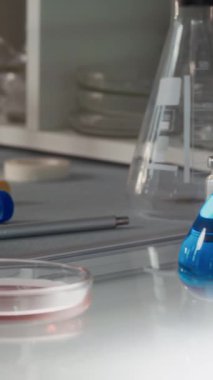 Dikey olarak, laboratuarda el yazısıyla yapıştırılmış test tüpleri ve mataralarla iş masasını çeken kimse yok.