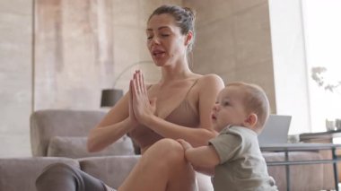 Ayakları protezli dişi yogiler evdeki lastik paspasın üzerinde oturmuş meditasyon yaparken tapılası bir bebek yakınlarda oturuyor.