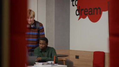 Kıdemli erkek profesör akademik projede çeşitli genç öğrencilere ders saatleri dışında ders çalışma saatleri ve gelişigüzel öğrenme sahneleri sırasında masadaki dizüstü bilgisayarı göstermelerini tavsiye ediyor.