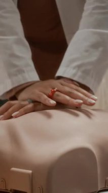 Siyahi genç kızın üniversitedeki tıp öğrencileri için eğitim sınıfında manikin üzerinde suni teneffüs yaptığı dikey eğim.